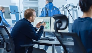 male-electrical-engineer-inspecting-pcb-part-at-desk