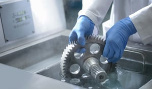 Worker cleaning a mechanical part using an ultrasonic parts washer